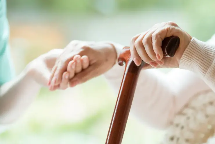 A senior caregiver holding an elderly resident's hands