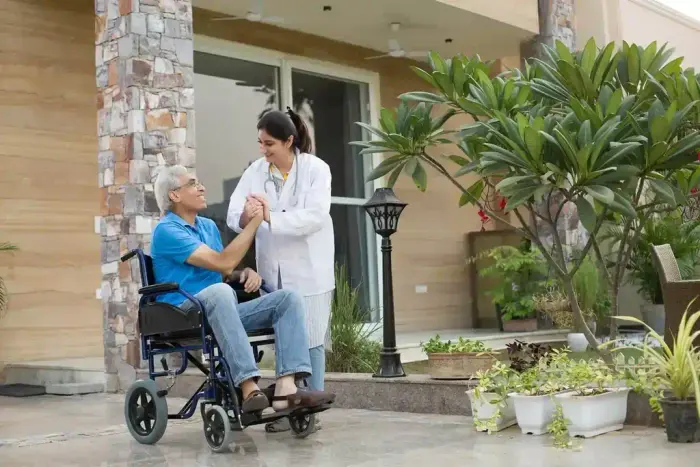 A caregiver holding hands with a smiling senior resident in a garden